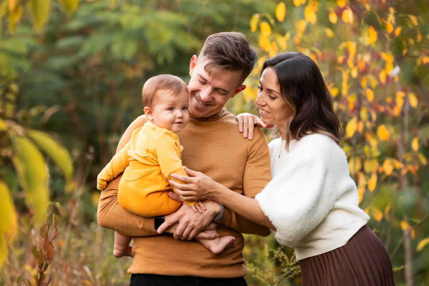 A smiling family with their baby outdoors